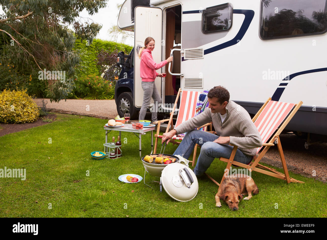 Couple In Van Enjoying Barbeque On Camping Holiday Stock Photo