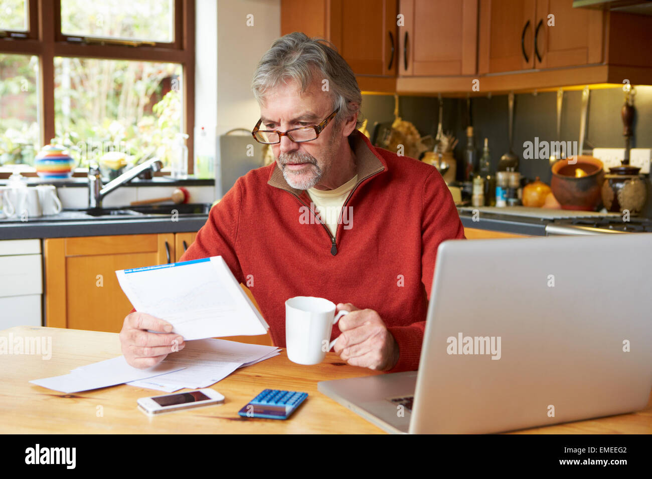 Mature Man Looking At Home Finances In Kitchen Stock Photo