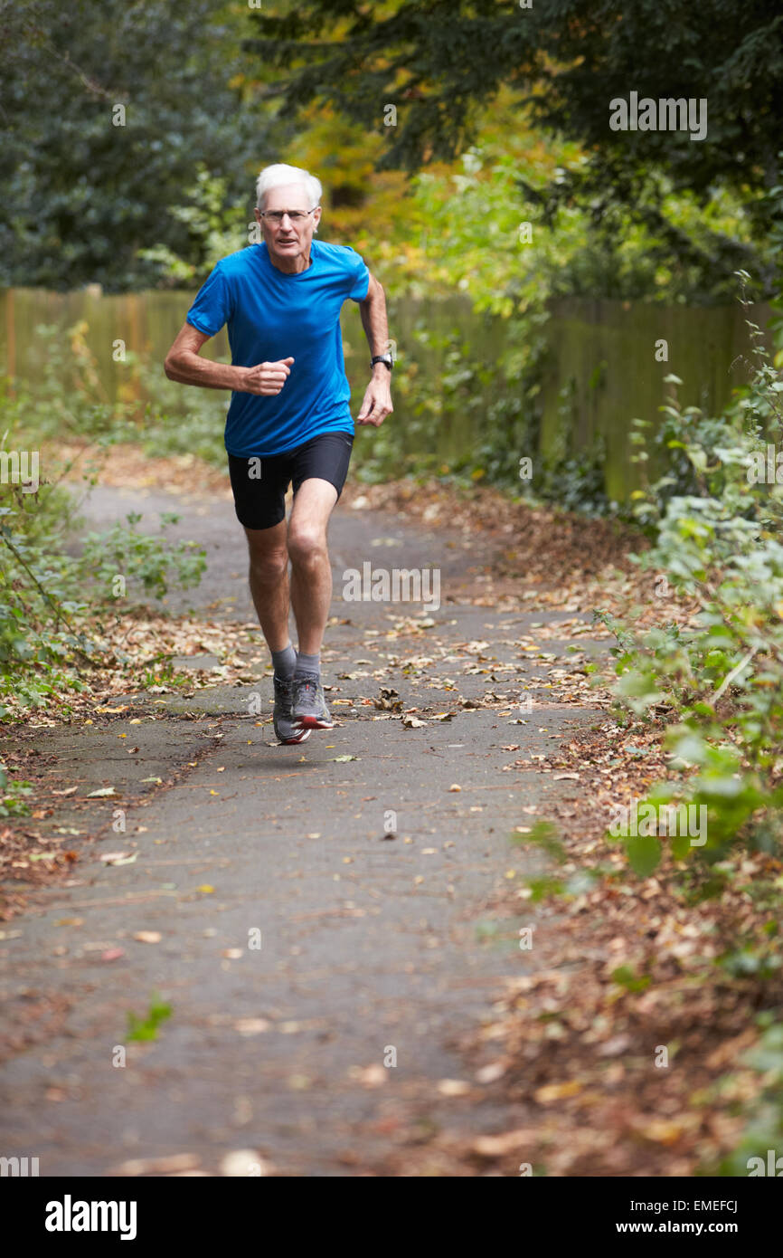 Mature Male Jogger Running Along Path Stock Photo