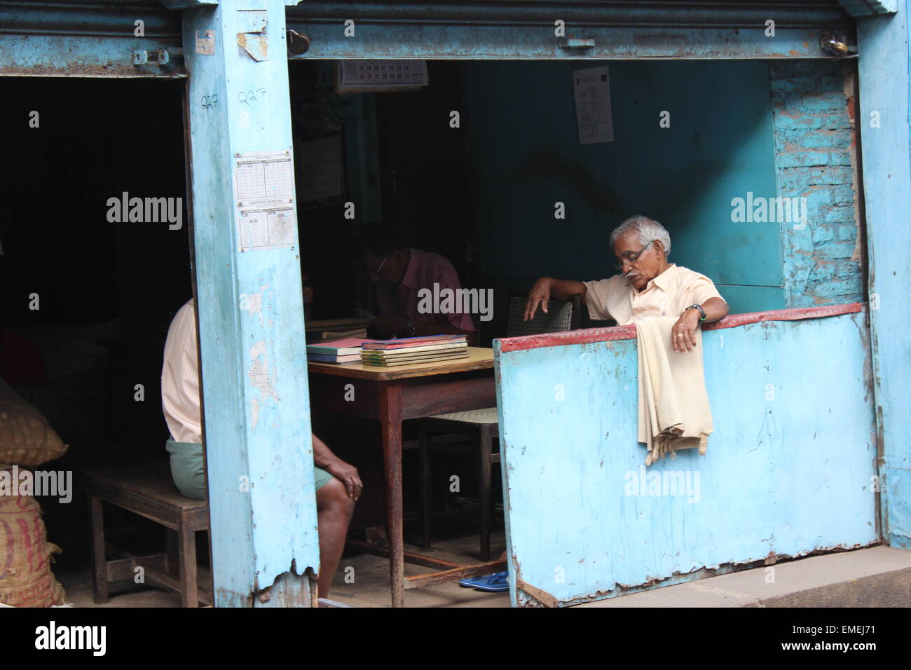 An old man dozes in an open-front godown (warehouse) in Mattancherry Stock Photo