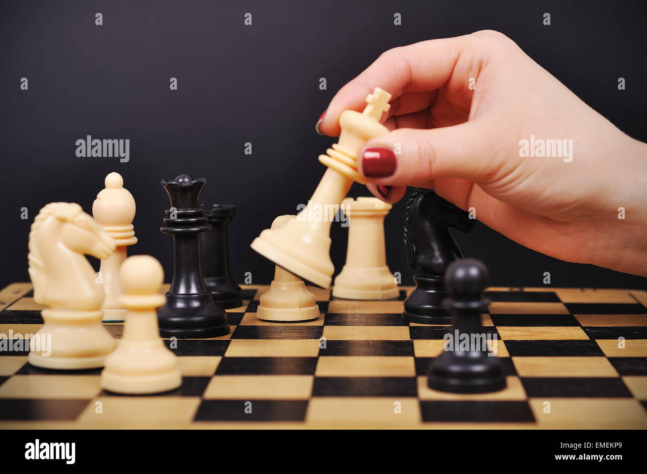 Chess player hand making move with white queen to checkmate