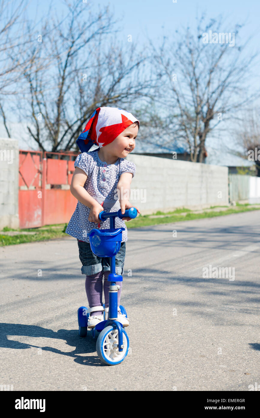 Beautiful baby girl rides tricycle in summer Stock Photo Alamy