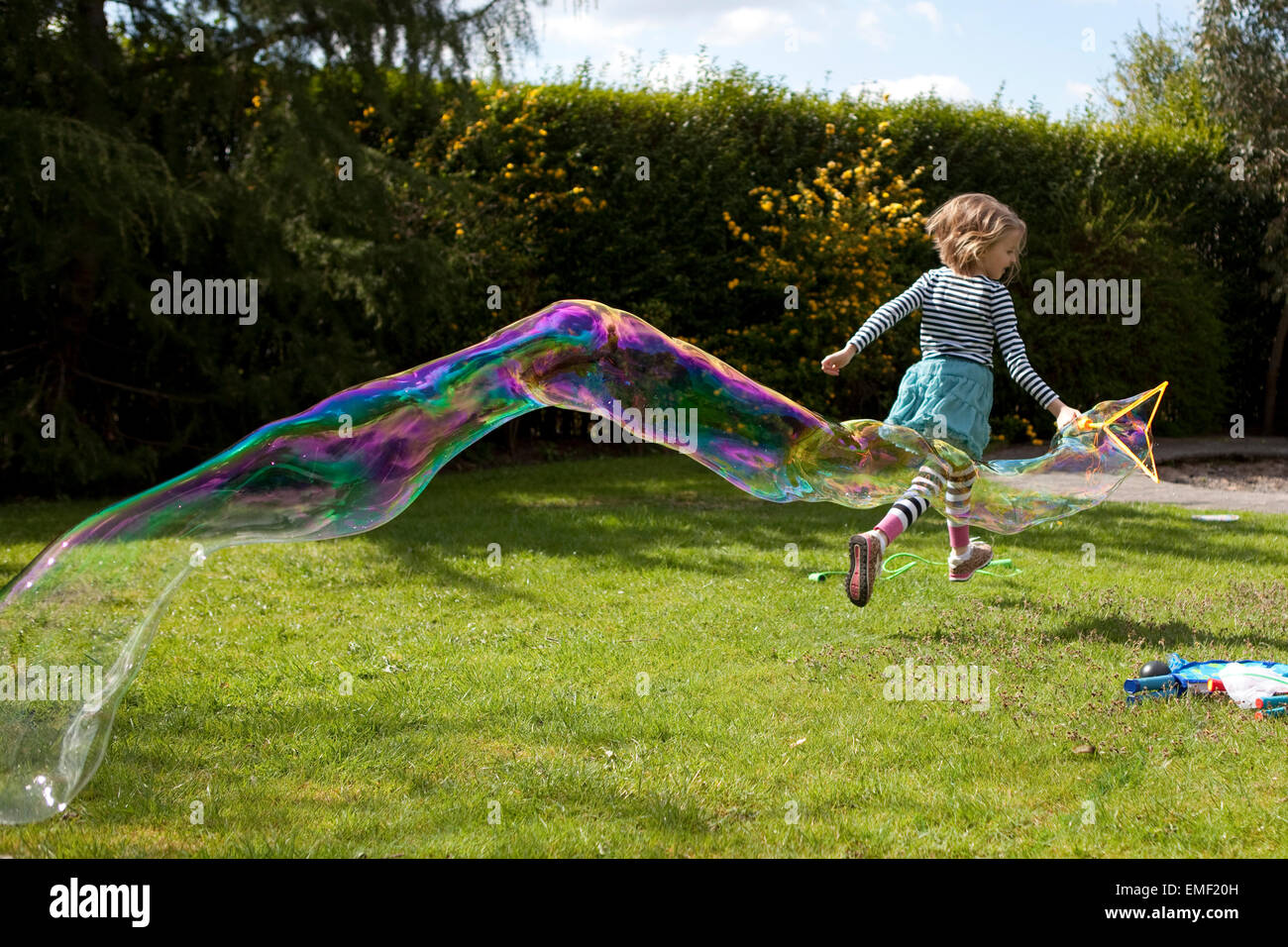 Young girl running across grass with giant bubble Stock Photo Alamy