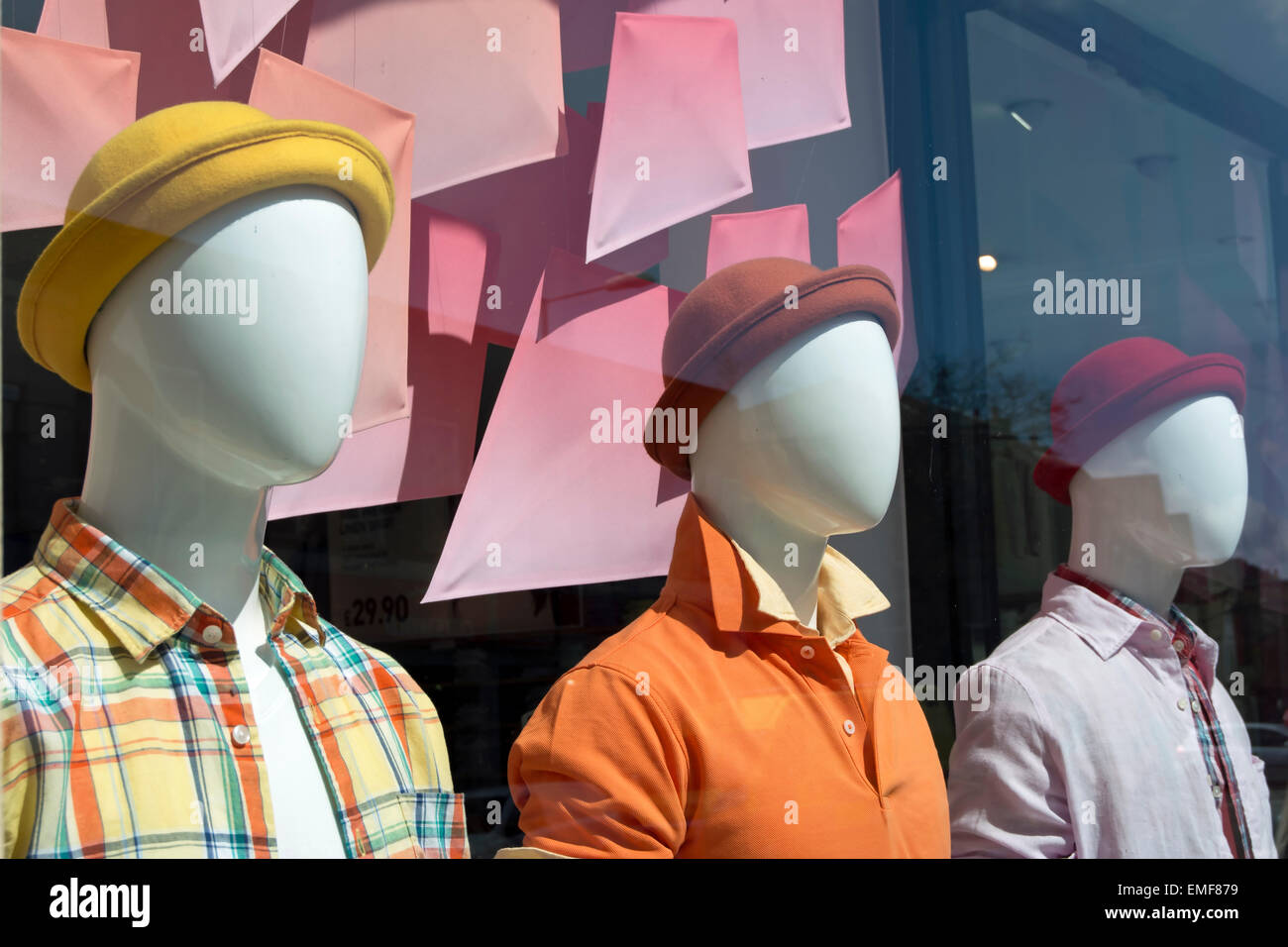 mannequins in coloured hats and shirts in a clothing shop window in