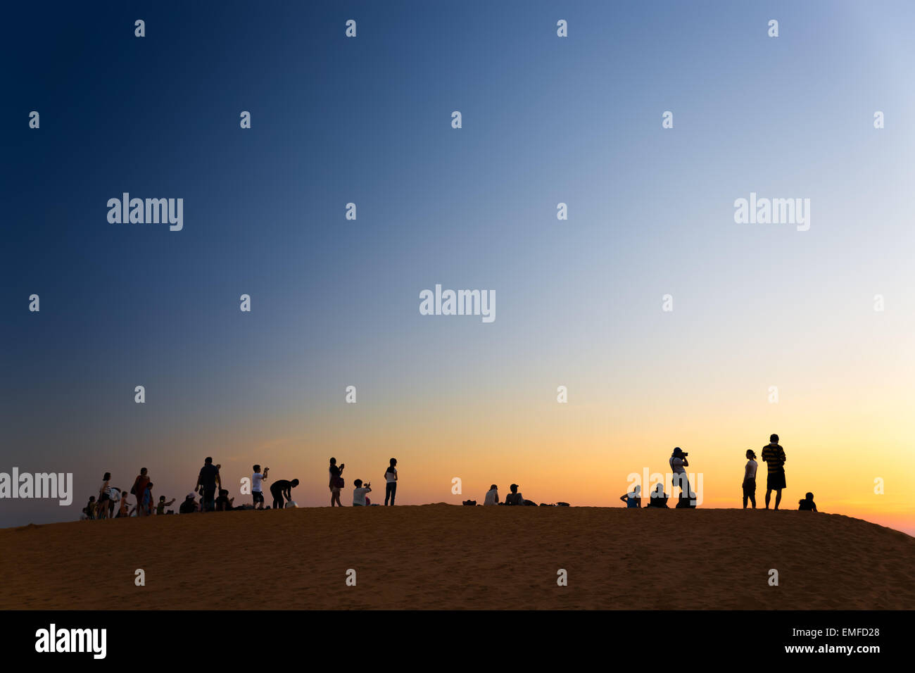 MUI NE, VIETNAM - FEBRUARY 08, 2014: Tourist watching sunset on red sand dunes close to South China Sea Stock Photo