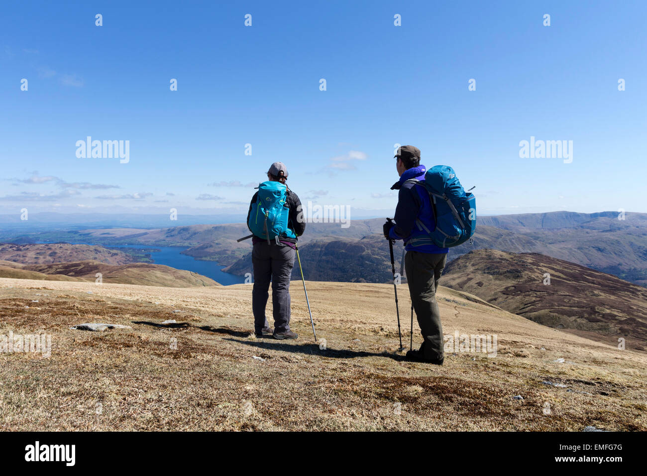 Two Walkers Enjoying View Over Ullswater on a Sunny Spring Day From the Hill of White Stones Lake District Cumbria UK Stock Photo