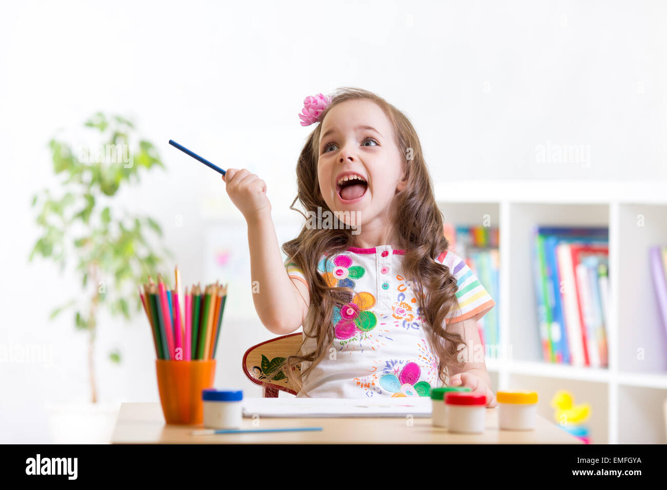 Cheerful child girl drawing with pencils in preschool Stock Photo