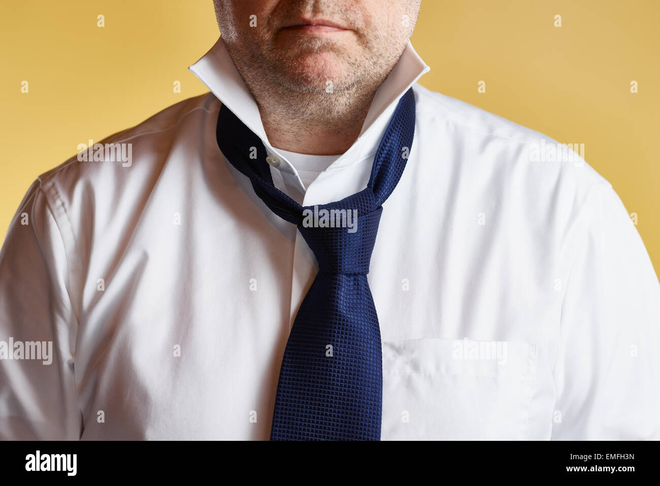Close up, male wearing white shirt and blue tie, loose tie, yellow background Stock Photo
