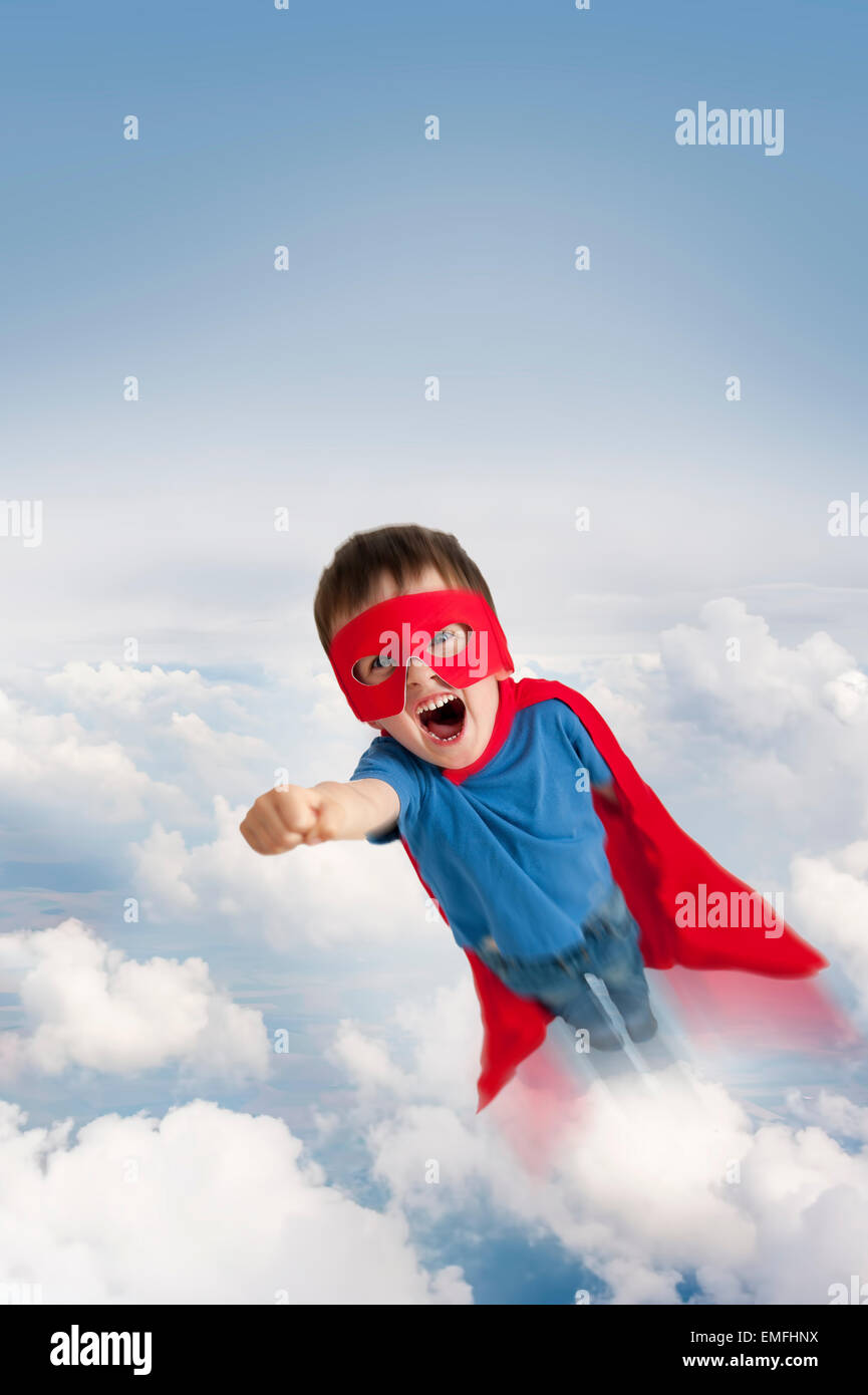 superhero boy flying in the sky through clouds Stock Photo