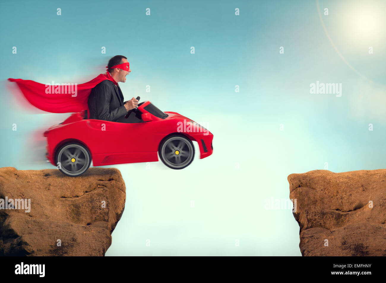 man in a red car jumping a gap ravine challenge Stock Photo