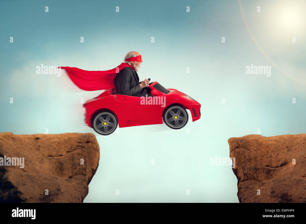 active senior superhero driving a car off a ravine Stock Photo
