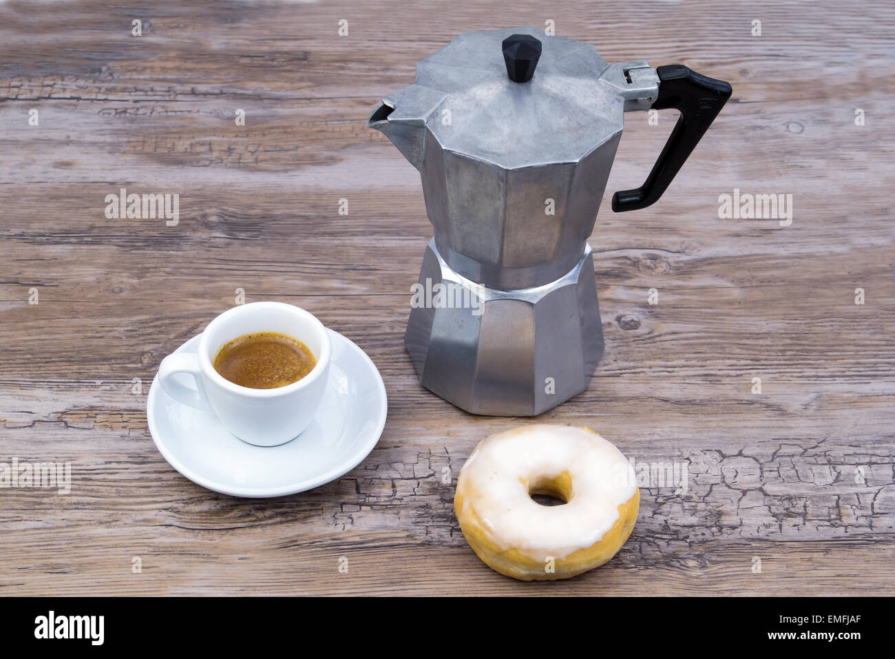Espresso with espresso maker and a glazed donut on a wooden table from