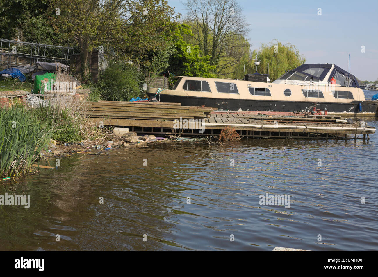 Motor boat cruiser at the shoreline River Thames with floating rubbish in the water Stock Photo