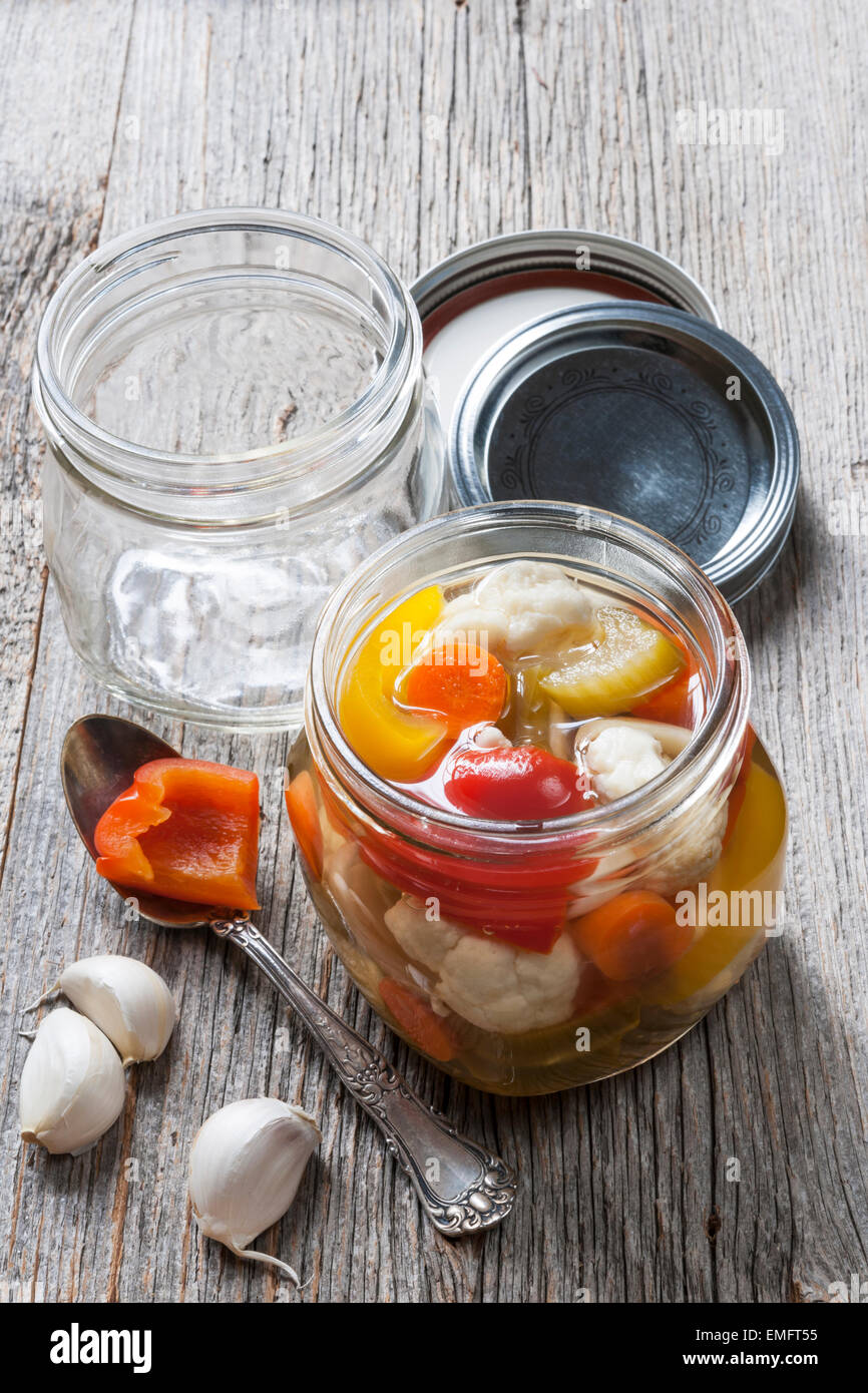 Home preserving mixed vegetables by pickling in glass canning jars Stock Photo