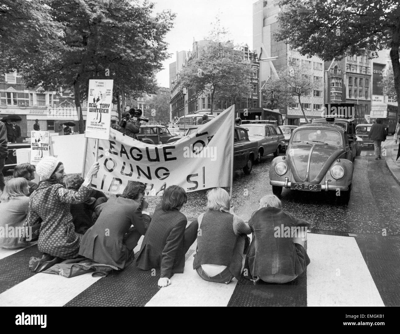 A group of young Liberals stop traffic by sitting on a pedestrian crossing in a busy London street in protest against the Government's Immigration Bill. Drivers of vehicles were asked to show passes by Ashley Wood who dressed in a South African policeman's uniform. 18th June 1971. Stock Photo