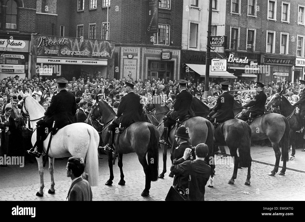 Mounted police seen here trying to control a large crowd gathered in Ridley Road E8 after former fascist leader Sir Oswald Mosley had been assaulted at a rally in London's East End. He and members of his anti-Semitic Blackshirt group were assaulted and punched to the ground as soon as his meeting opened at Ridley Road, Dalston. Police closed the meeting within the first three minutes and made 54 arrests one of the arrested was Sir Oswald's son Max. 2nd August 1962 Stock Photo