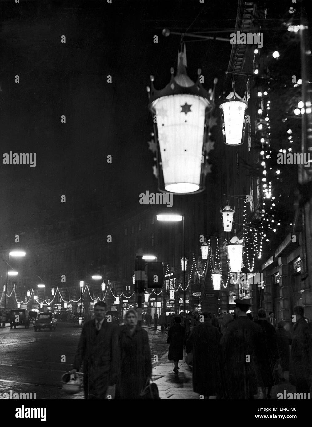 Shoppers walk underneath hanging illuminations on Regent Street after the Christmas lights were turned on. 28th November 1958. Stock Photo