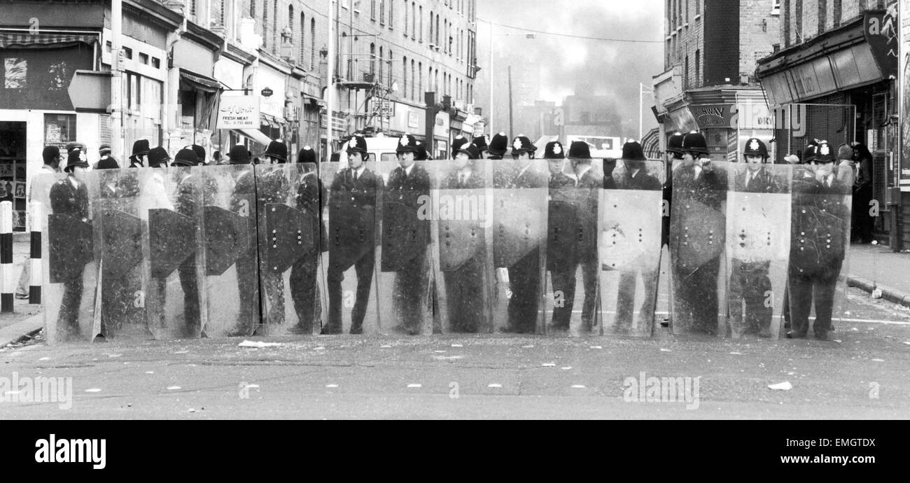 Policemen with riot shields form a cordon during the riots in Brixton April 11th 1981. The riots were sparked off by the stabbing of a black youth combined with tensions caused by the Metropolitan Police's Operation Swamp which began a week earlier. The operationw involved plain clothes police officers being dispatched into Brixton within five days almost 950 people were stopped and searched through the heavy use of the sus law - which allowed police to stop and search any individual on the basis of 'suspicion' of wrong-doing. Stock Photo