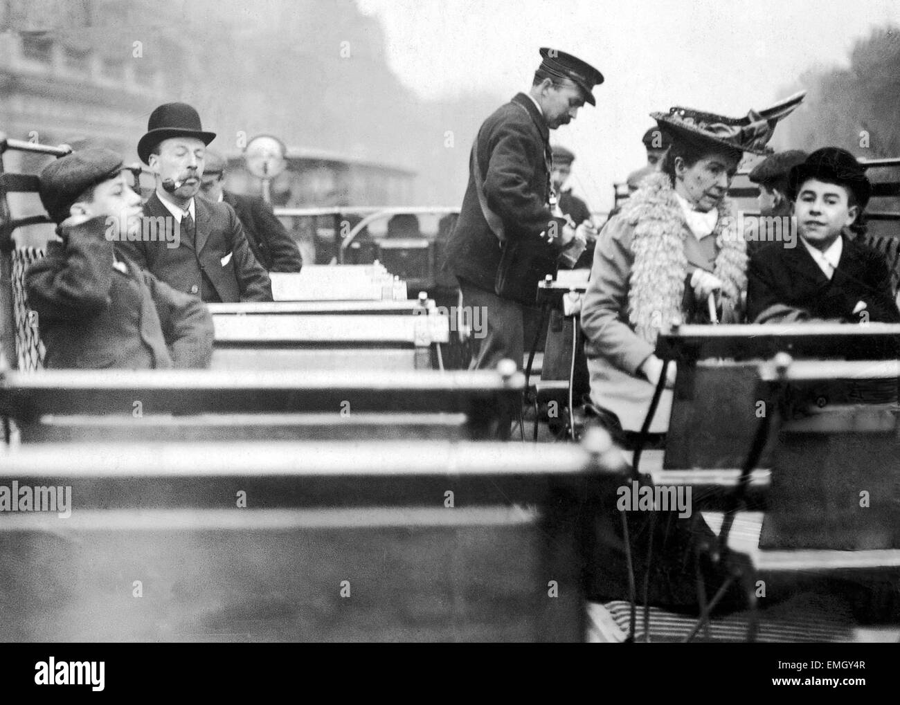 A conductor checks for passengers tickets on the open top deck of a London tram. These tickets were used as part of a Daily Mirror promtion with a prize awarded to a winning ticket number. 22nd May 1906. Stock Photo