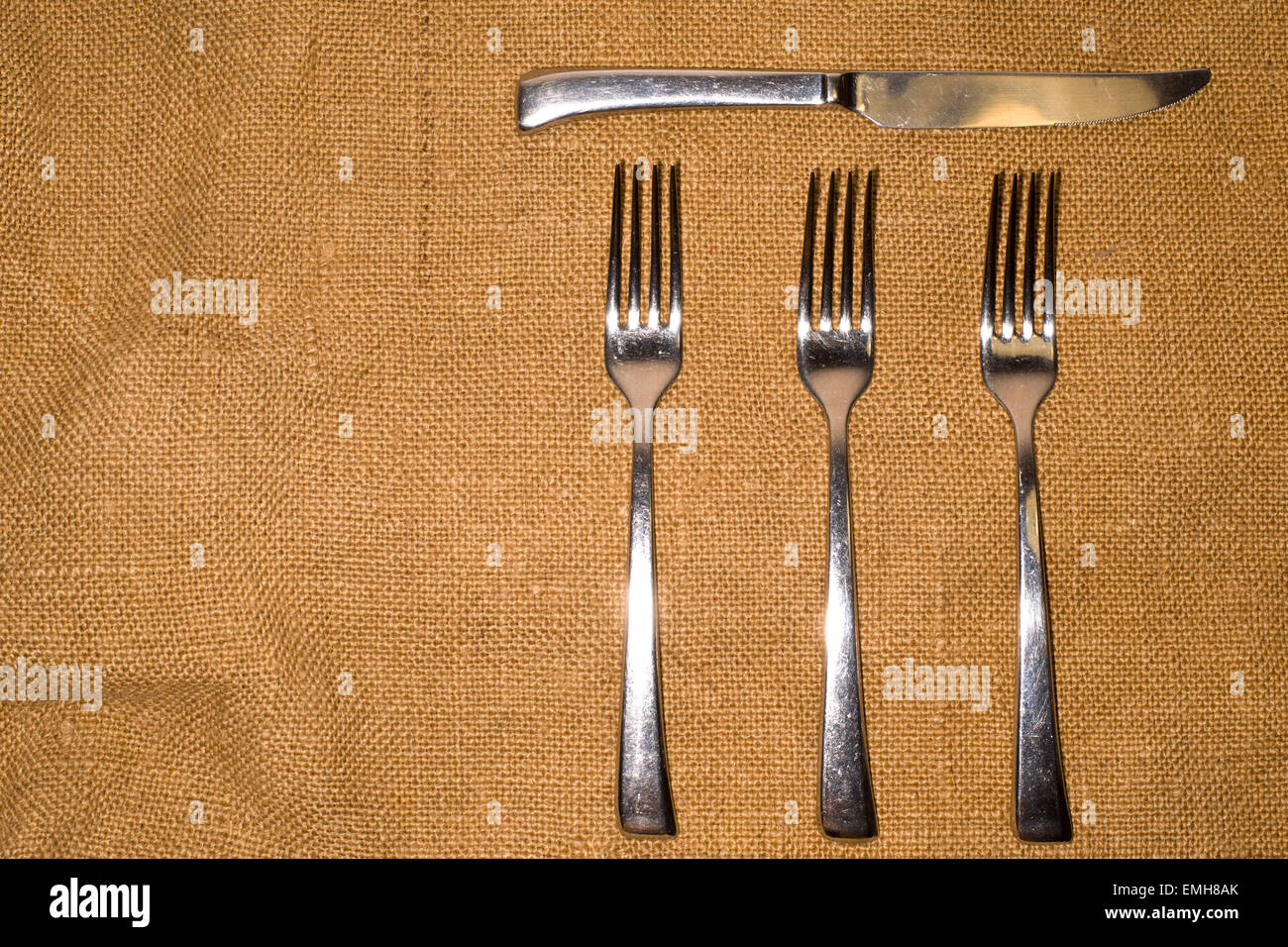 Three forks and knife on an old tablecloth Stock Photo