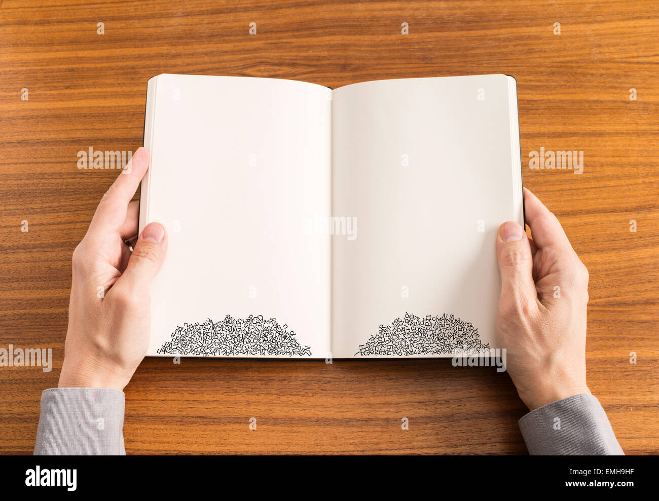 Hands of man holding book. The text on the pages have fallen and are stacked on the bottom of the pages. Conceptual image of difficulty with reading and spelling. Stock Photo