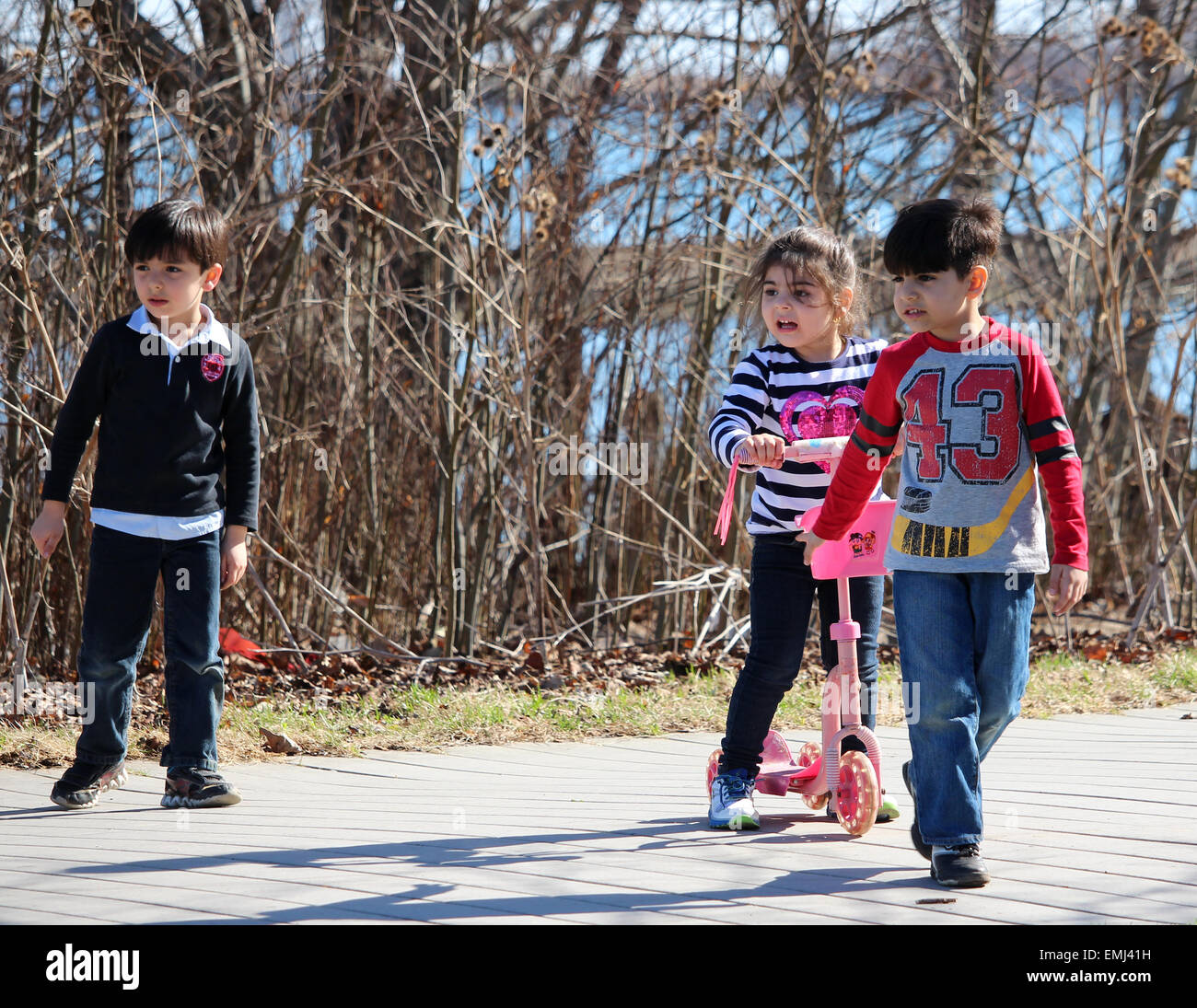 Three young children having fun on the boardwalk along Lake Ontario in the Spring. Stock Photo