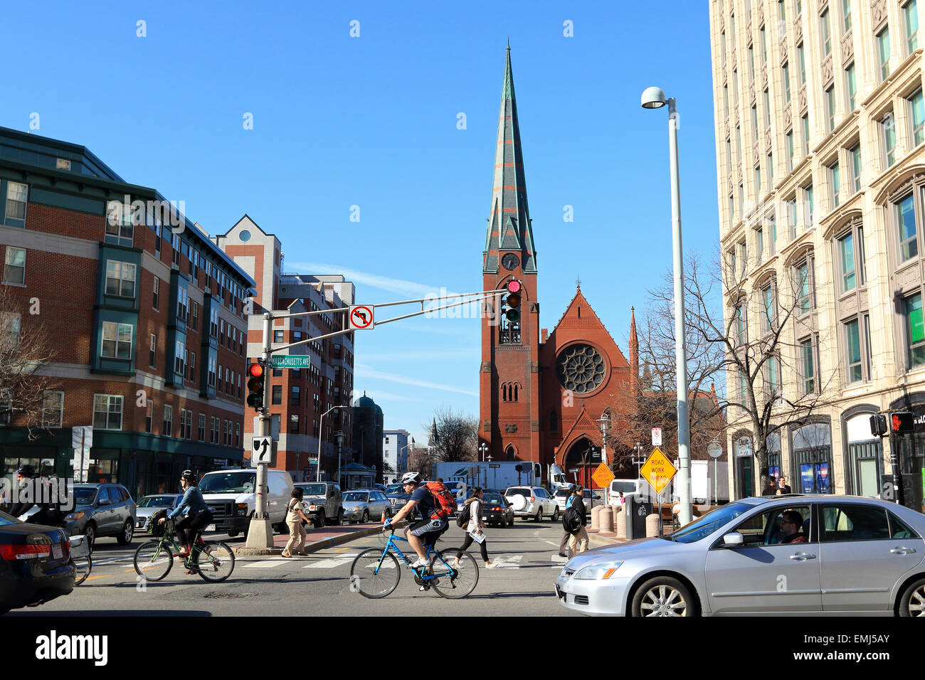 Cambridge city street commuters on bike and in car pass First Baptist Church spire, Cambridge, Massachusetts, USA. Stock Photo