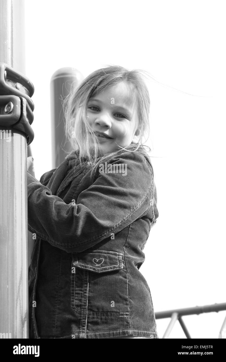 black and white of a 6 year old girl smiling at a playground. Stock Photo