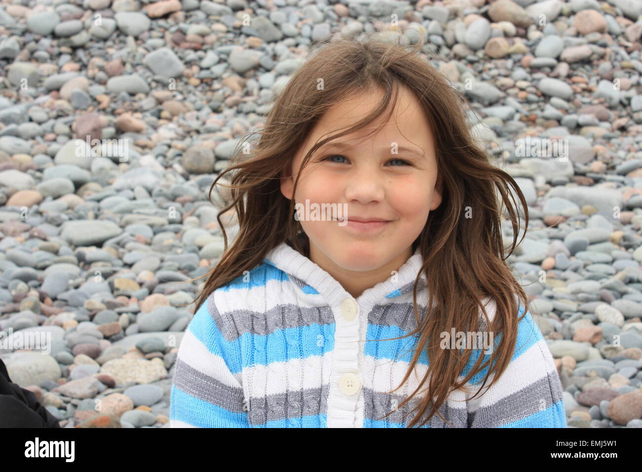 6 year old girl, smiling, on a rocky beach.  Halifax, Nova Scotia Stock Photo