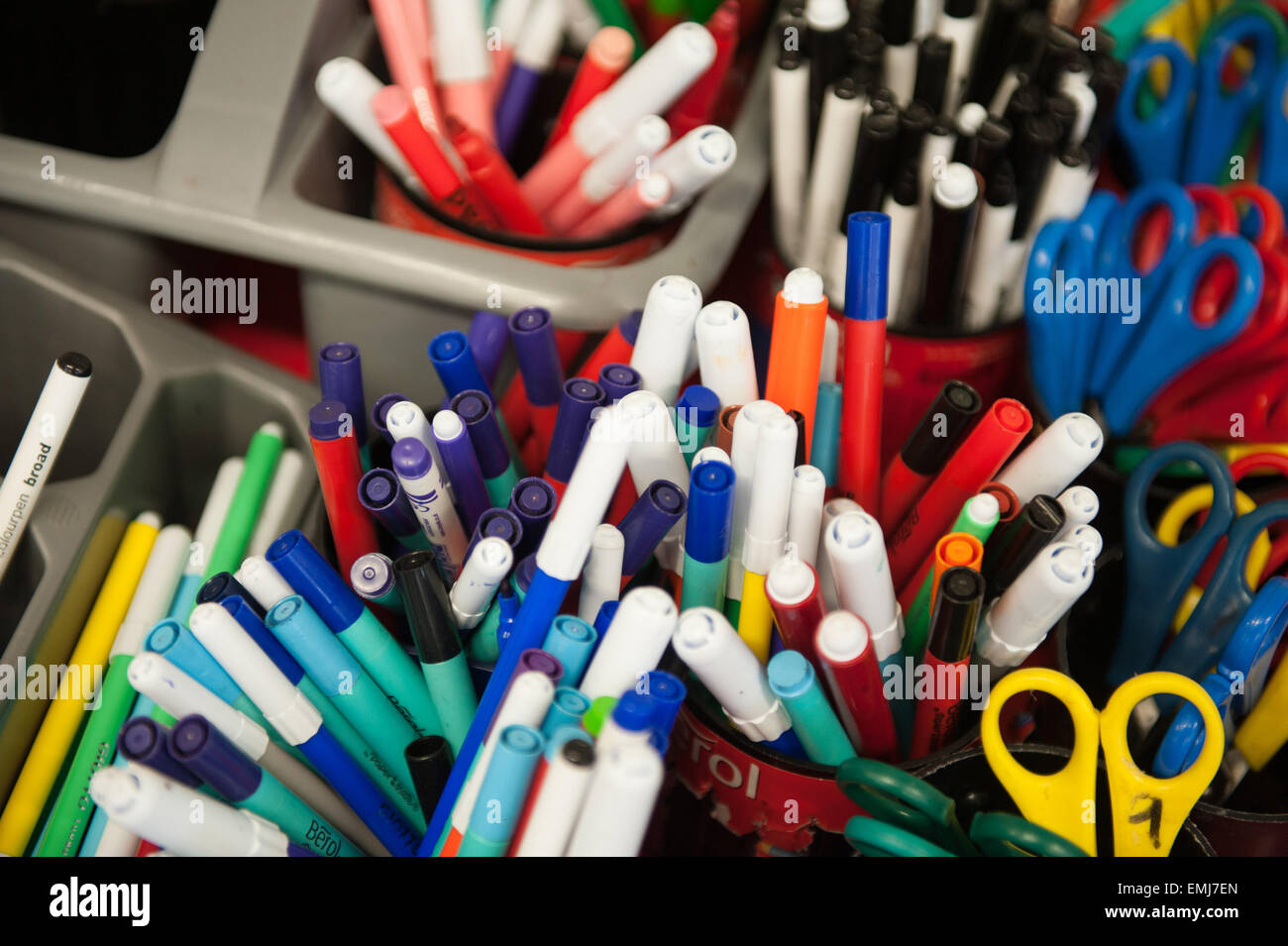 Boxes of felt tip pens and coloured pencils and scissors in a UK classroom Stock Photo