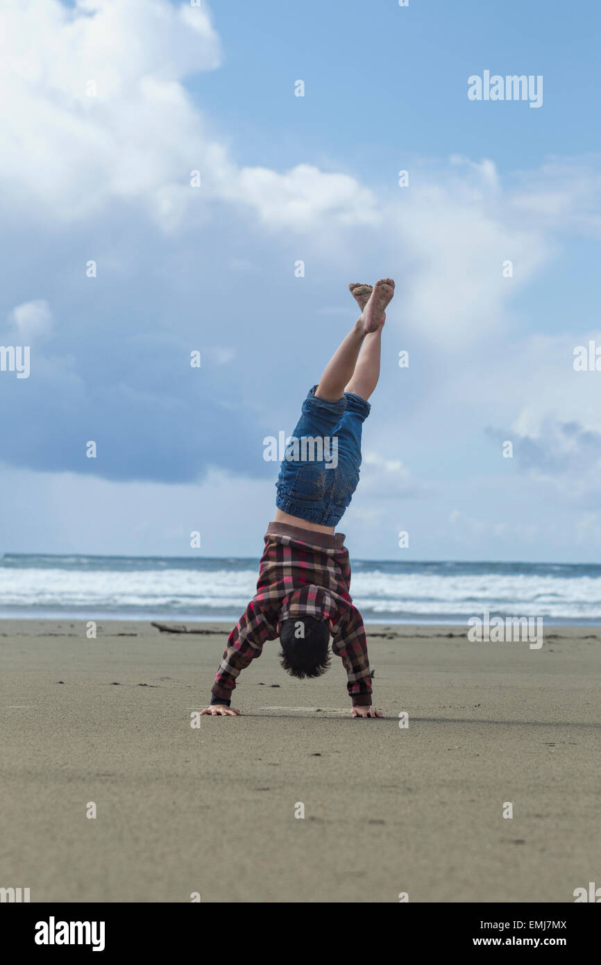 Boy does handstand on the beach in Newport, Oregon. Stock Photo