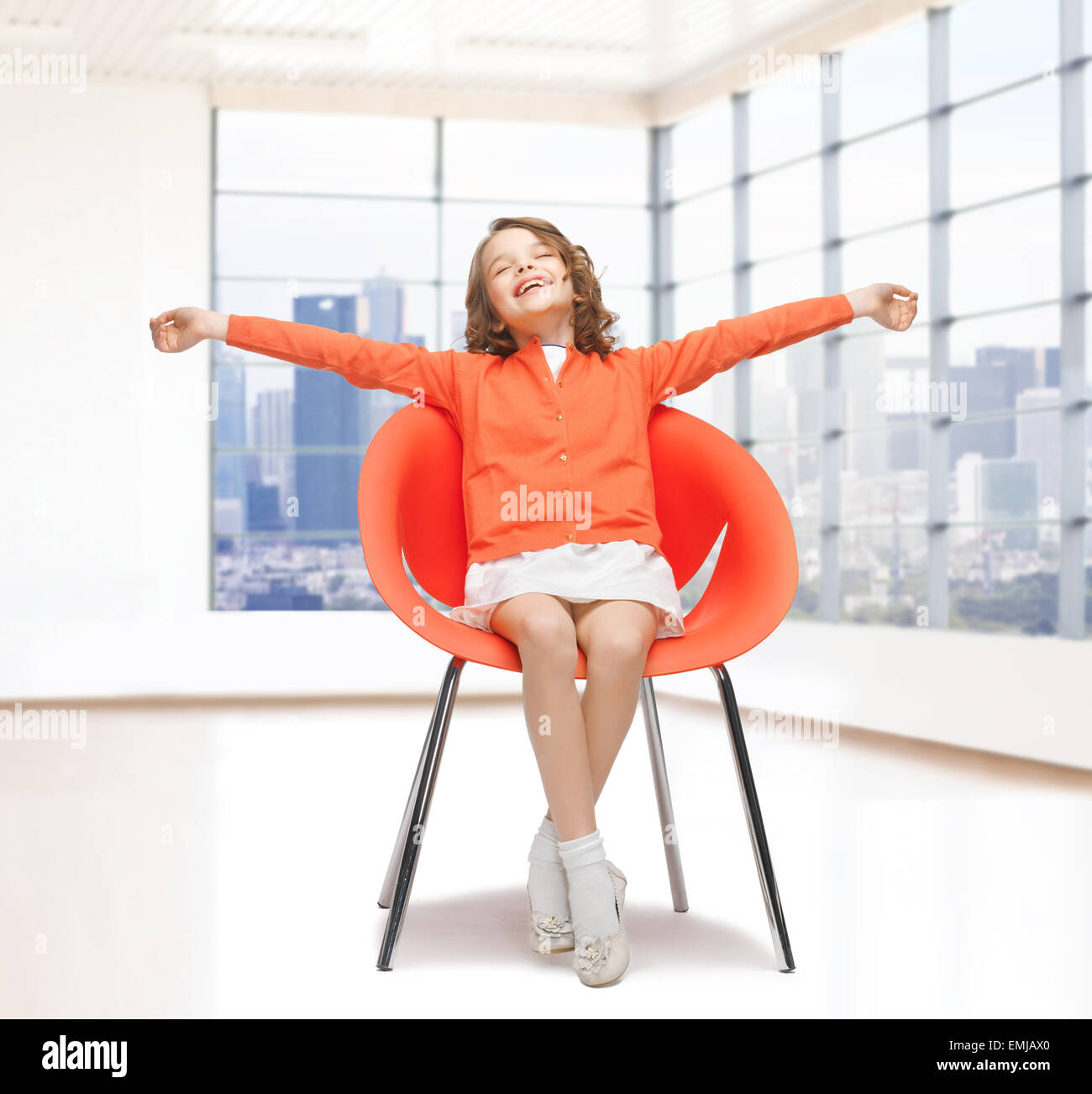 happy little girl sitting on designer chair Stock Photo - Alamy