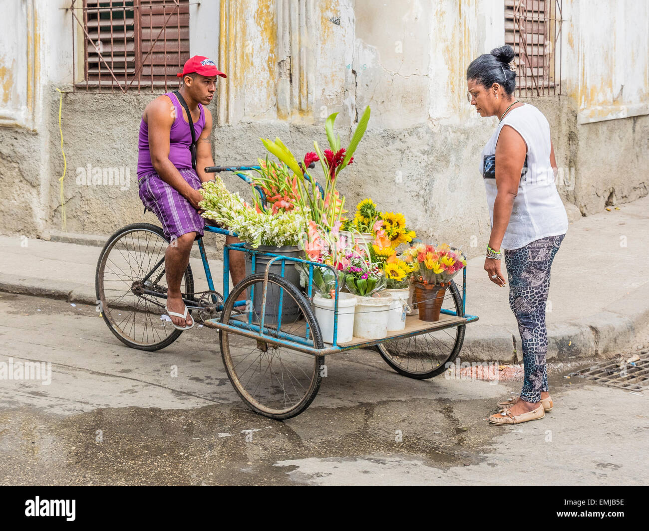 A Cuban woman looks over the offerings of a male flower cart vendor in