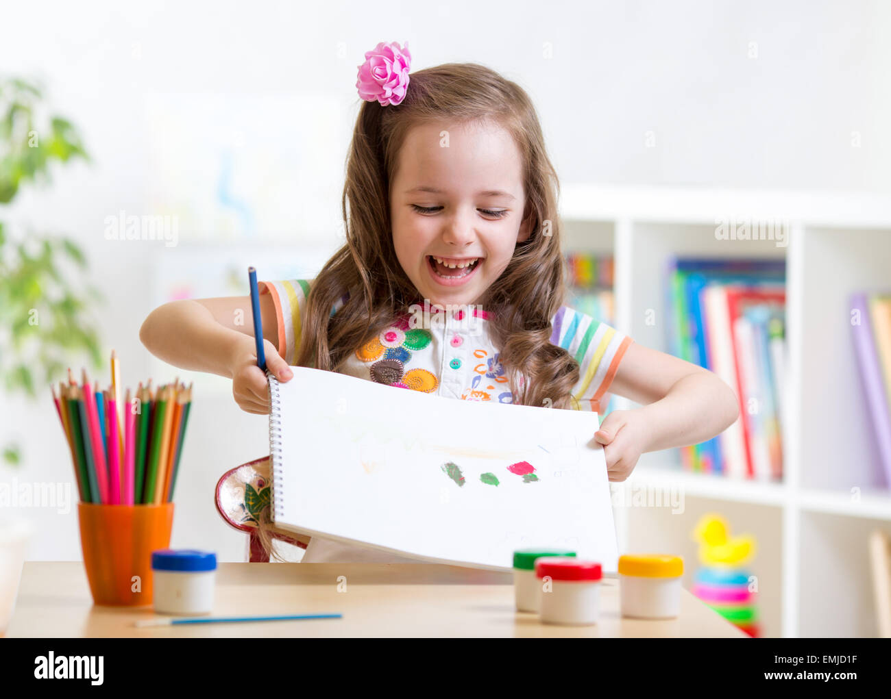 child girl painting and showing painting in nursery Stock Photo
