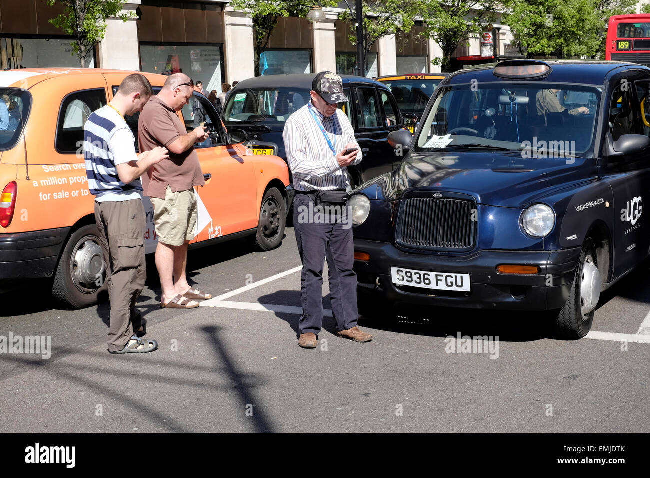 A black cab driver texts in the middle of the street during a protest against illegal touting. Stock Photo
