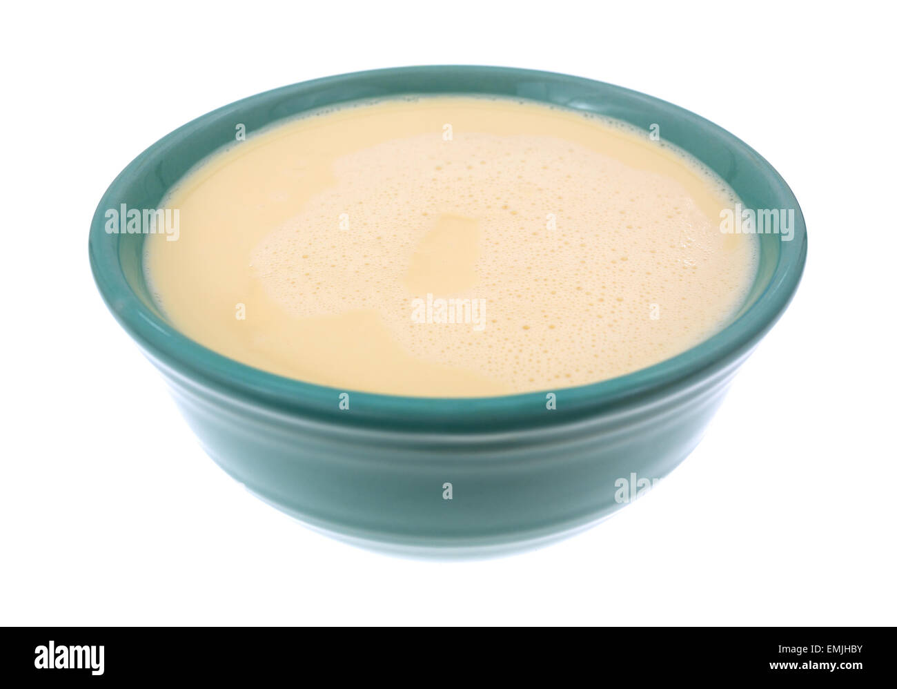 Side view of a bowl filled with evaporated milk on a white background. Stock Photo