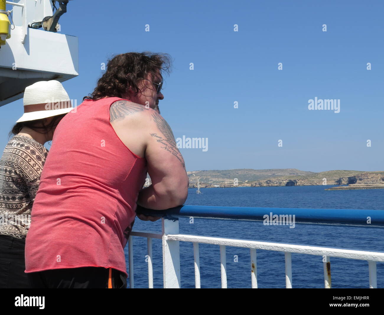 Fat bloke with tattoos leaning on the rails of a boat Stock Photo