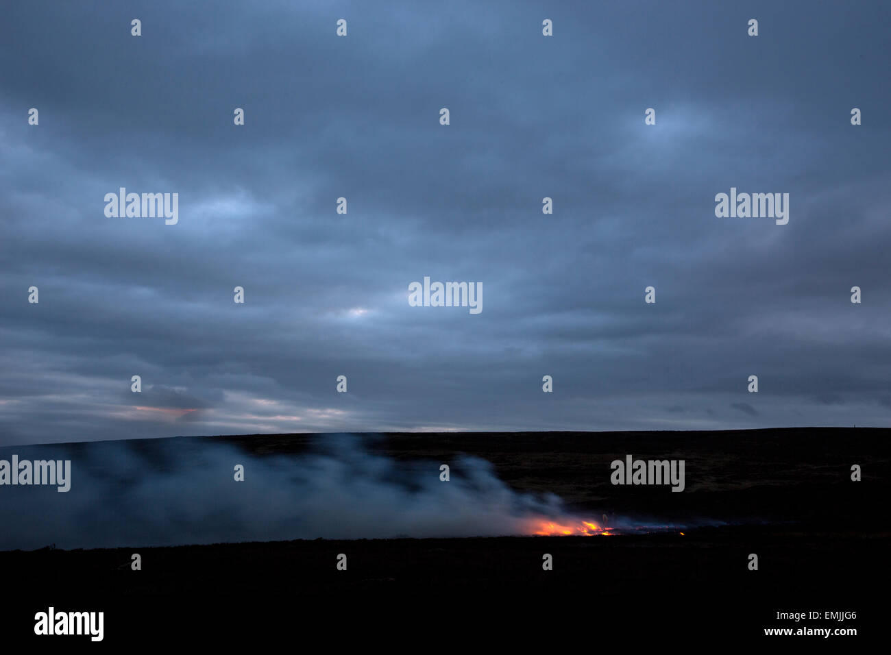 a controlled fire burns on in the evening on Ilkley Moor Stock Photo