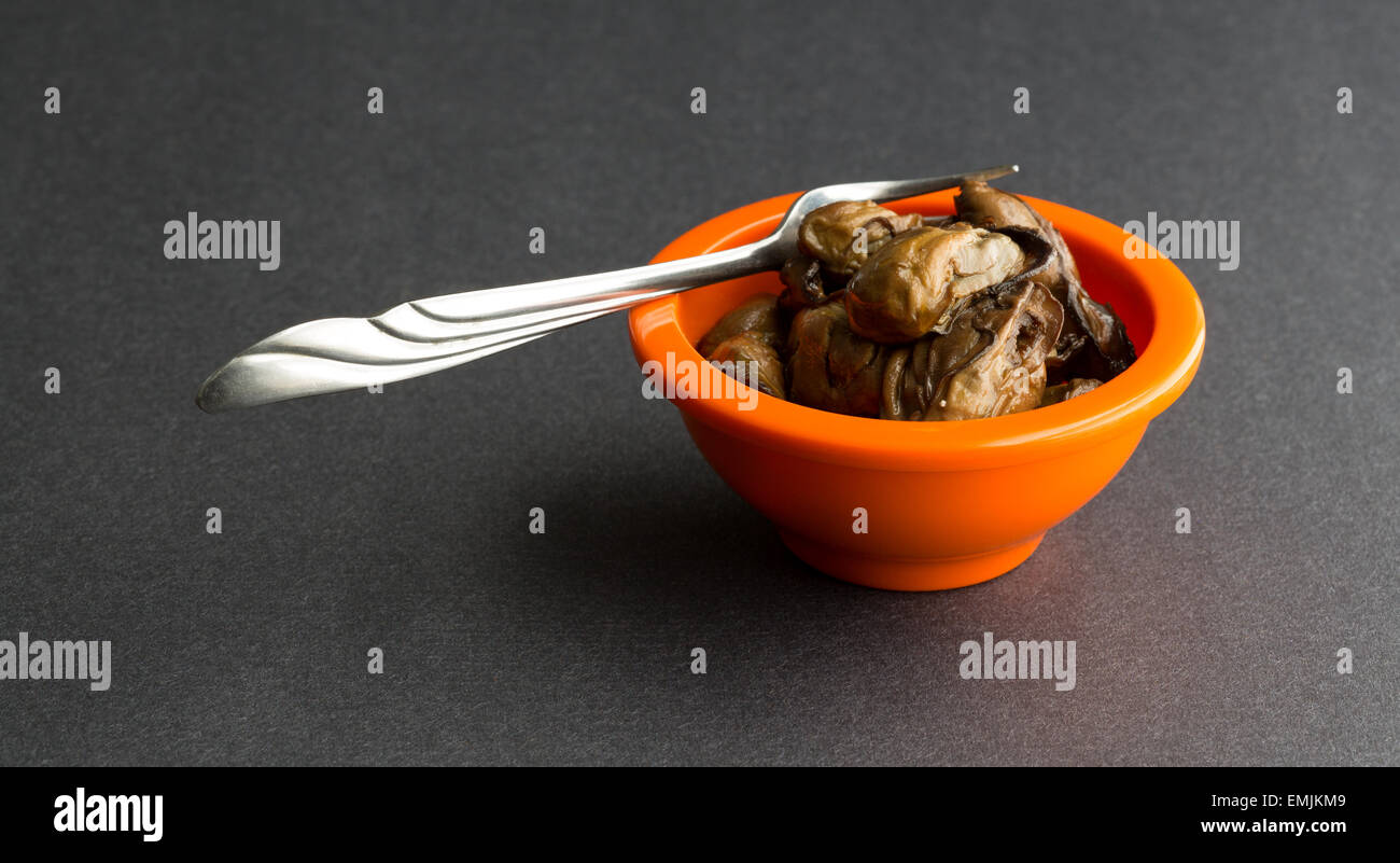 https://c8.alamy.com/comp/EMJKM9/a-small-orange-bowl-filled-with-small-whole-smoked-oysters-with-a-EMJKM9.jpg