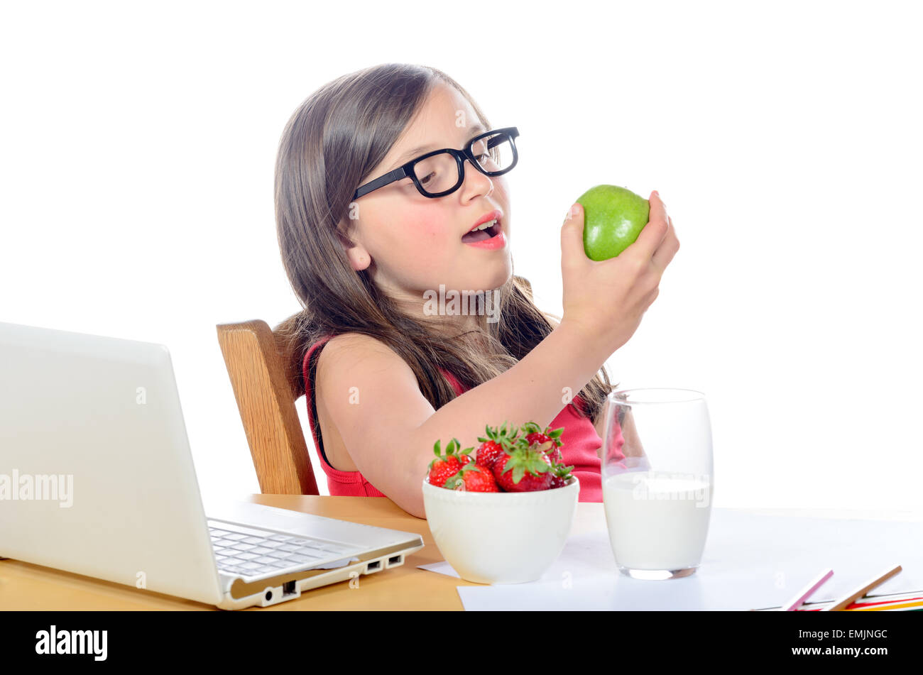 a little girl sitting at his desk eating an apple on white Stock Photo ...