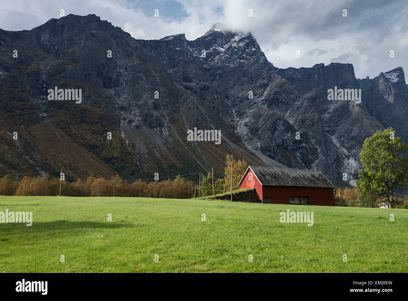 Farm field and barn with mountains of Trollveggen - Troll wall in background, Møre og Romsdal, Norway Stock Photo
