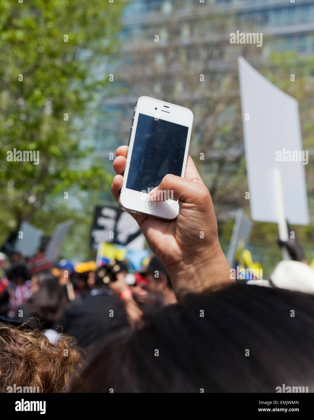 Man taking photo with iPhone above a crowd at a protest rally - USA Stock Photo