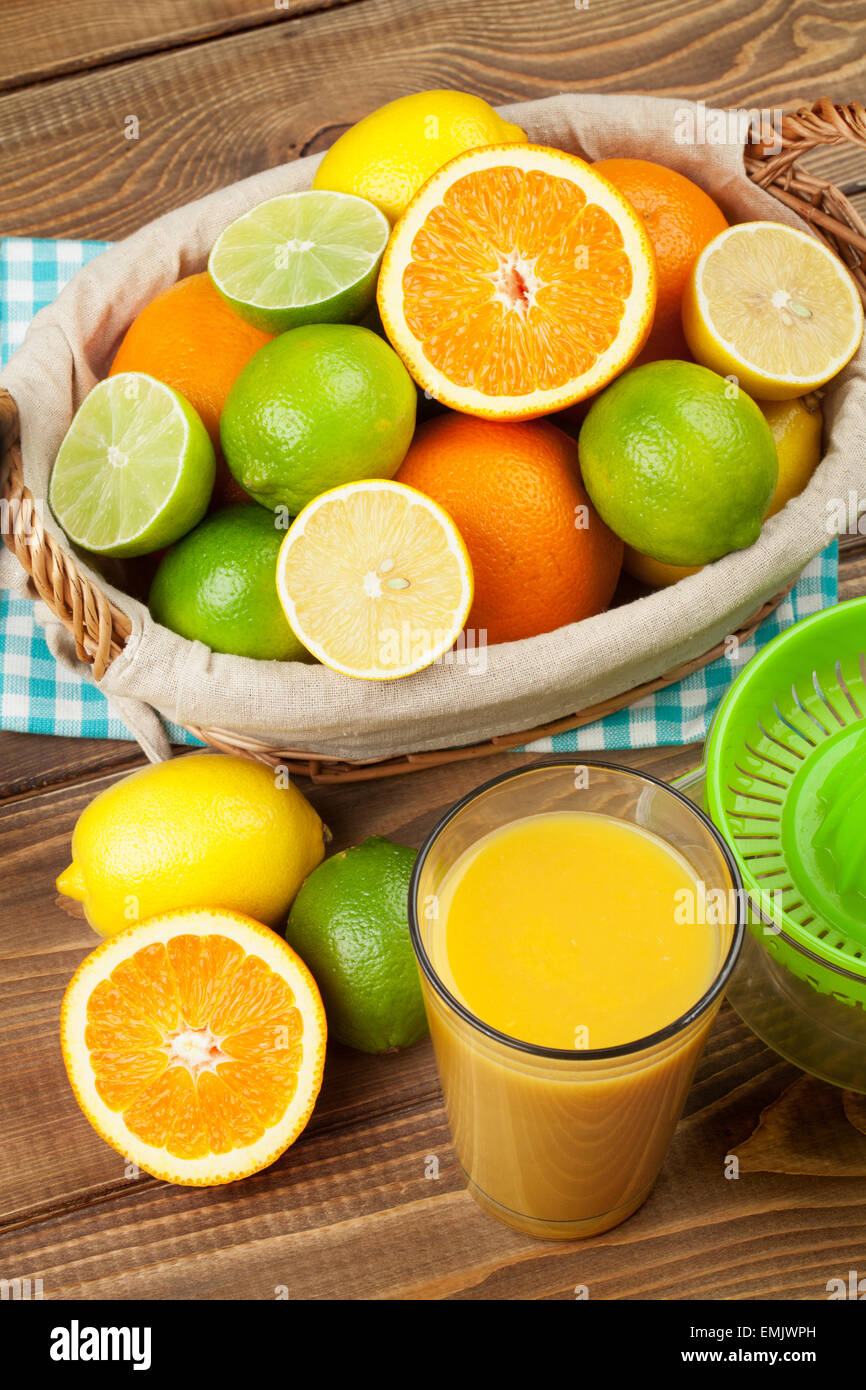 Citrus fruits and glass of juice. Oranges, limes and lemons. Top view over wood table background Stock Photo