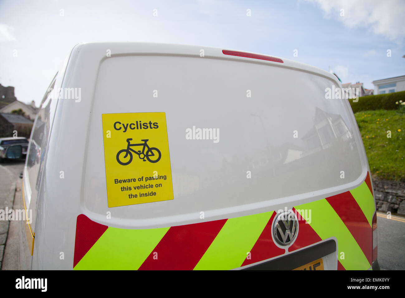 A warning sign on a white VW Transporter van 'Cyclists - beware of passing this vehicle on the inside' taken at the roadside Stock Photo