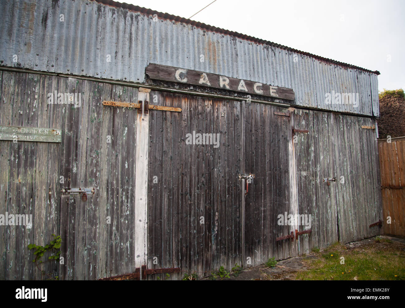 Disused corrugated steel & timber garages in Borth-y-Gest, Porthmadog with rust, flaking paint and hand-painted signage Stock Photo