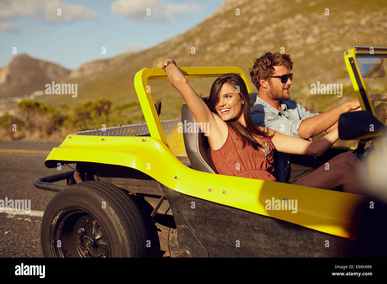 Relaxed couple enjoying in the car ride. Beautiful young woman looking at a view with her boyfriend driving the car on a summer Stock Photo