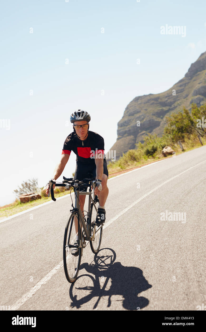 Shot of a male cyclist riding down a country road. Triathlete cycling on a bicycle. Stock Photo