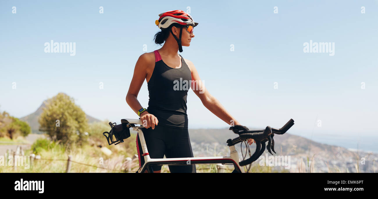 Image of determined female cyclist looking away. Fit woman wearing sportswear and cycling helmet looking at copyspace. Stock Photo