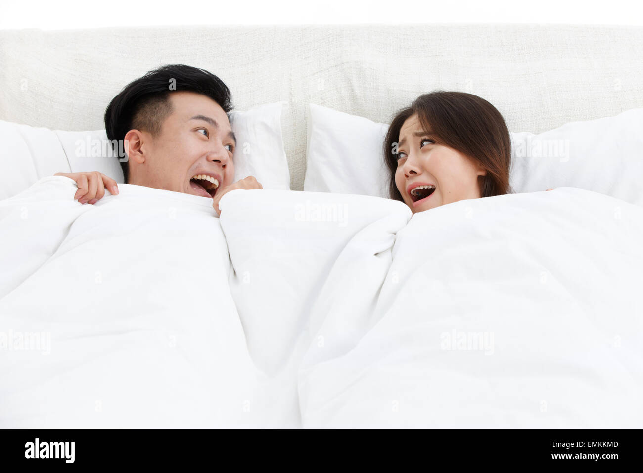 The two young men and women in the bed of the bedroom surprised shout Stock Photo