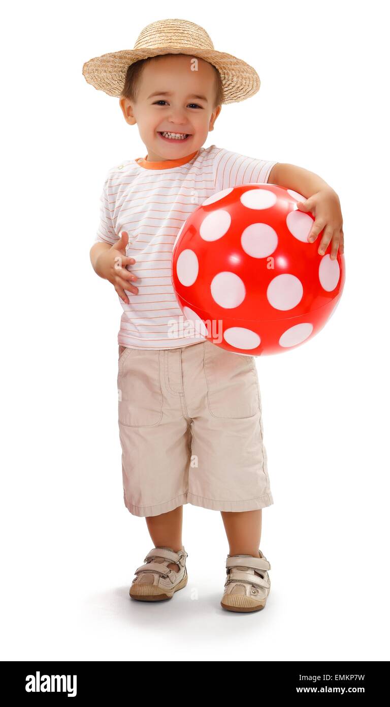 Cheerful little boy in straw hat, holding big red dotted ball Stock Photo